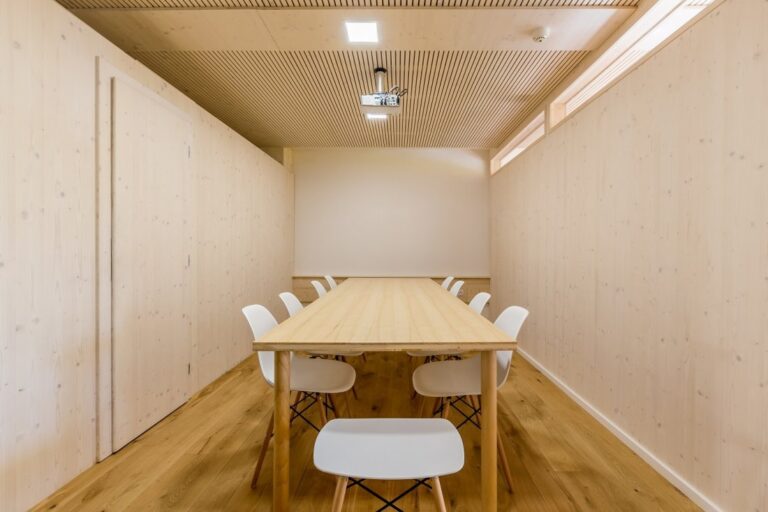 Zajímavá konferenční místnost s masivní podlahou feelwood, židelmi a dlouhým stolem