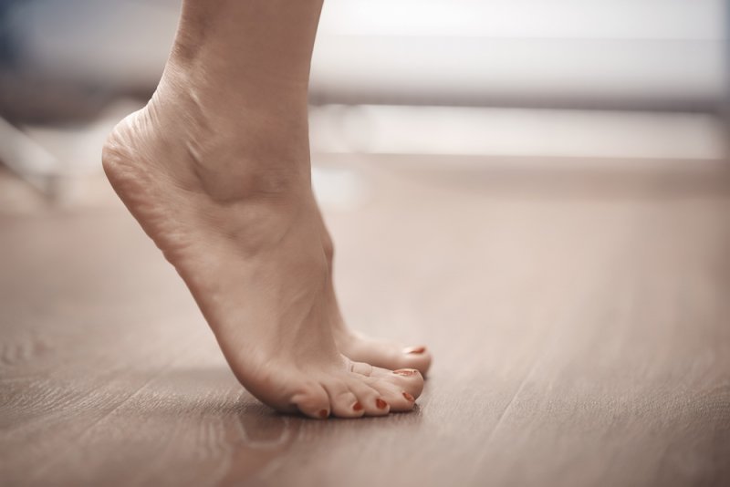 ženská noha šlapající na masivní podlahu FEEL WOOD